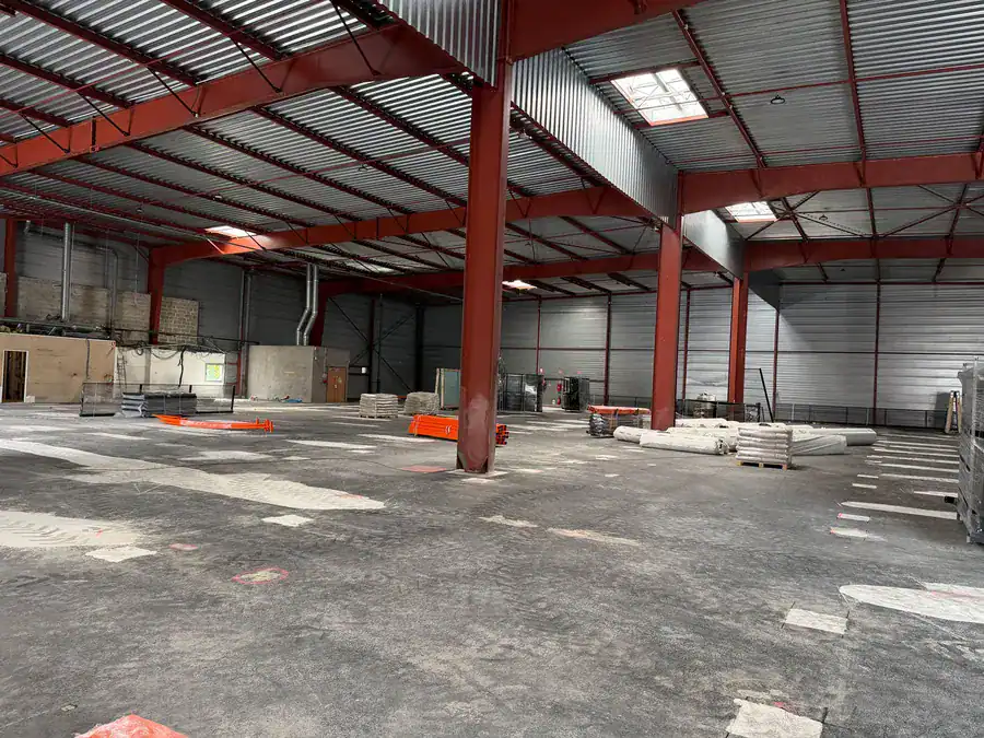 Chantier Padelcourt d'un terrain de padel dans un bâtiment existant : support en préparation, structure et vitrage sur palettes avant le montage