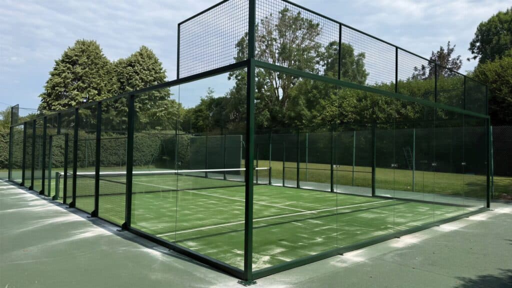 Terrain de padel panoramique construit par Padelcourt, chez un particulier du Calvados (14) : La piste panoramique livrée, gazon vert, structure vert foncé